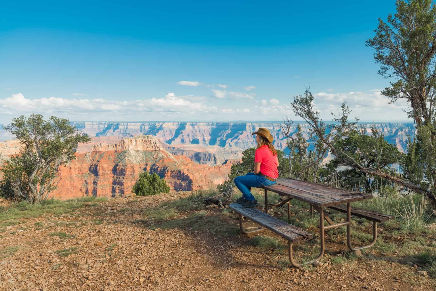 woman in cowboy hat sitting at Grand Canyon picnic table with view (Image: Shutterstock)