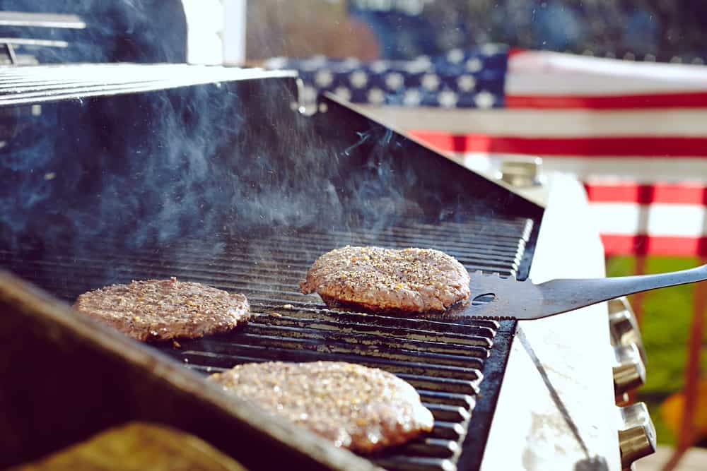 July 4th bbq grill hamburgers hot dogs american flag background