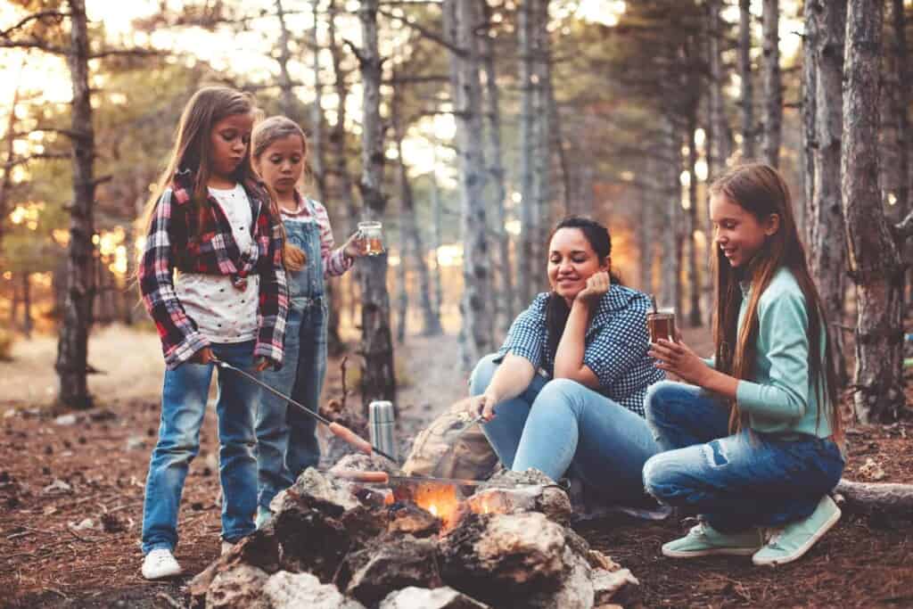 Mom and girls family around a campfire