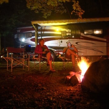 motorhome with couple sitting at campfire (Image: @rini2, iRV2 Forums)