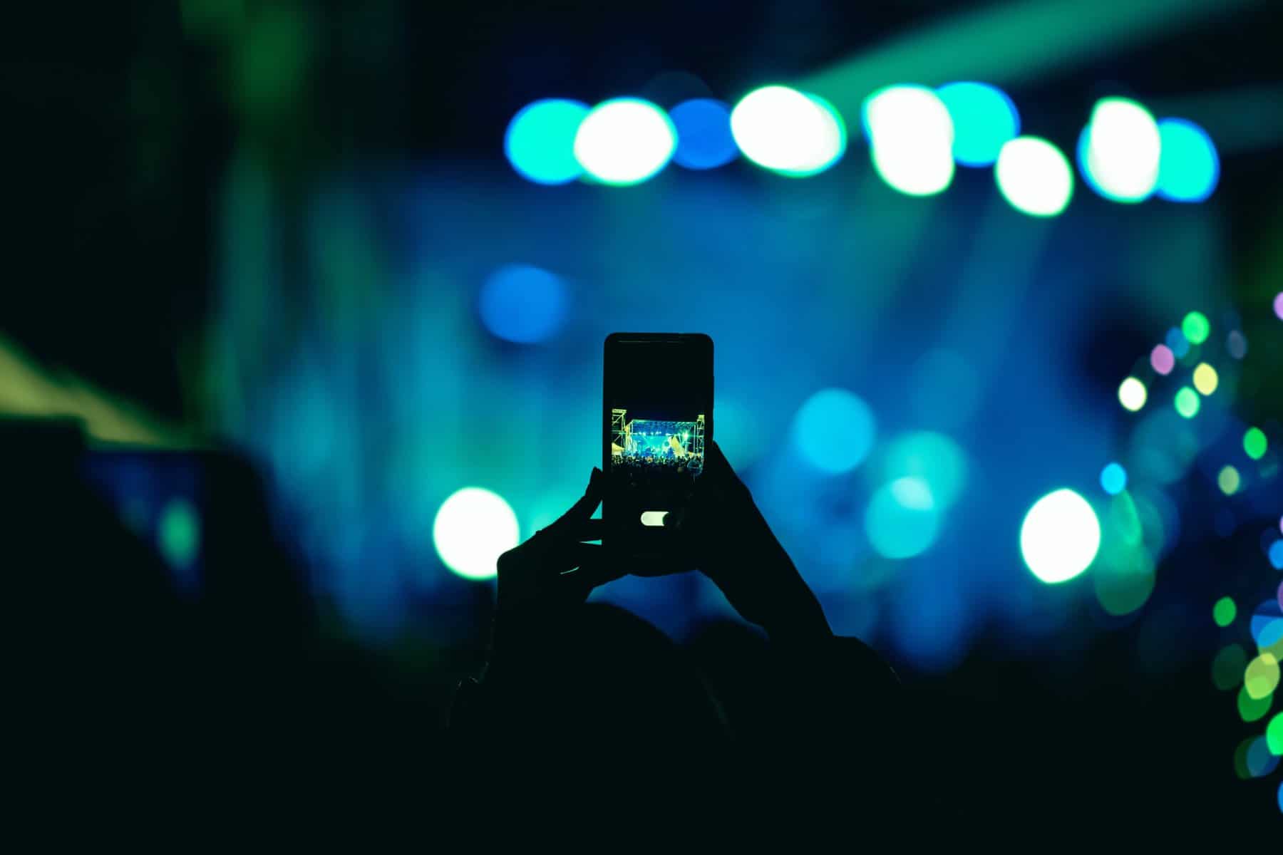 Concert attendee with phone while festival camping with your RV (Image: Shutterstock)